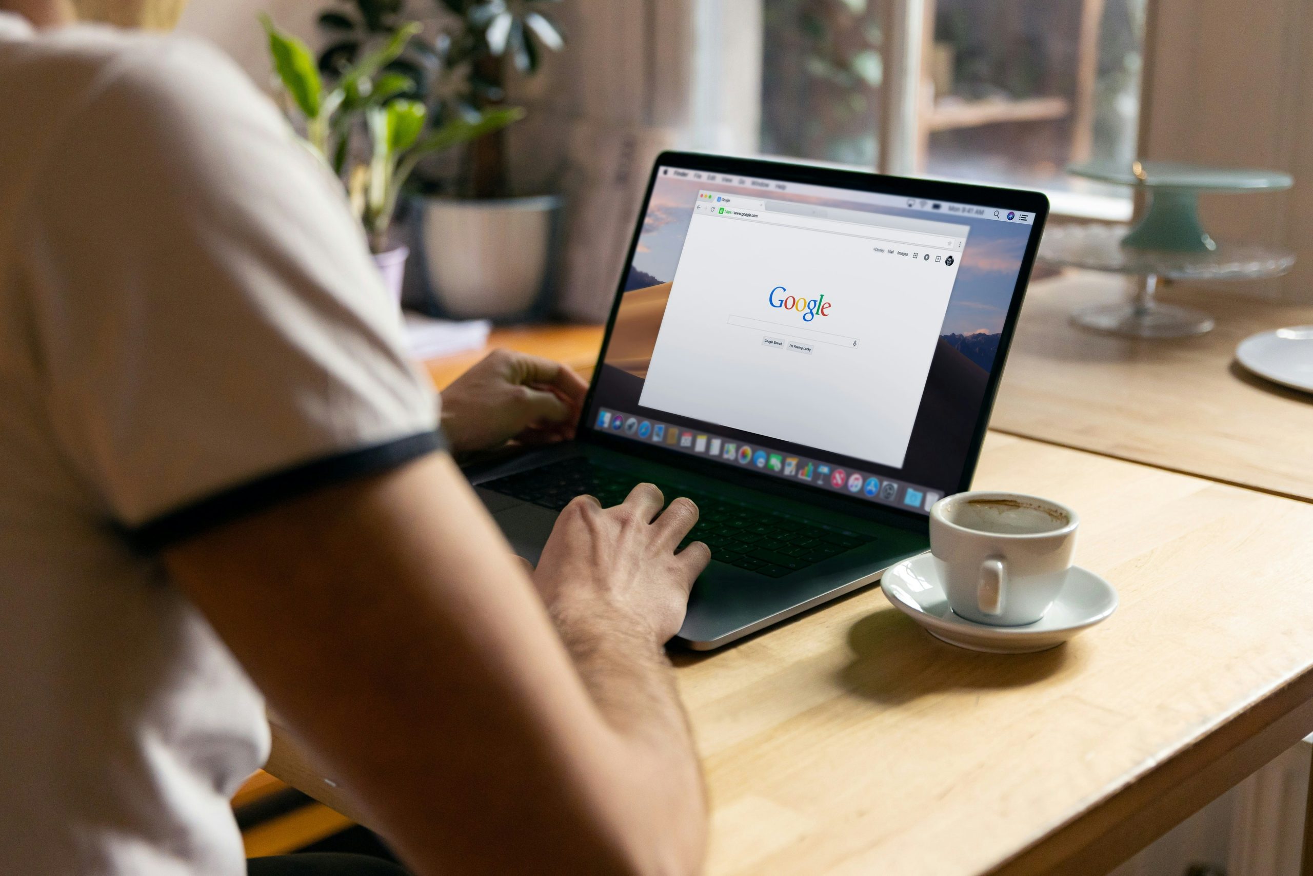 Personne de dos réalisant une recherche sur Google avec un ordinateur