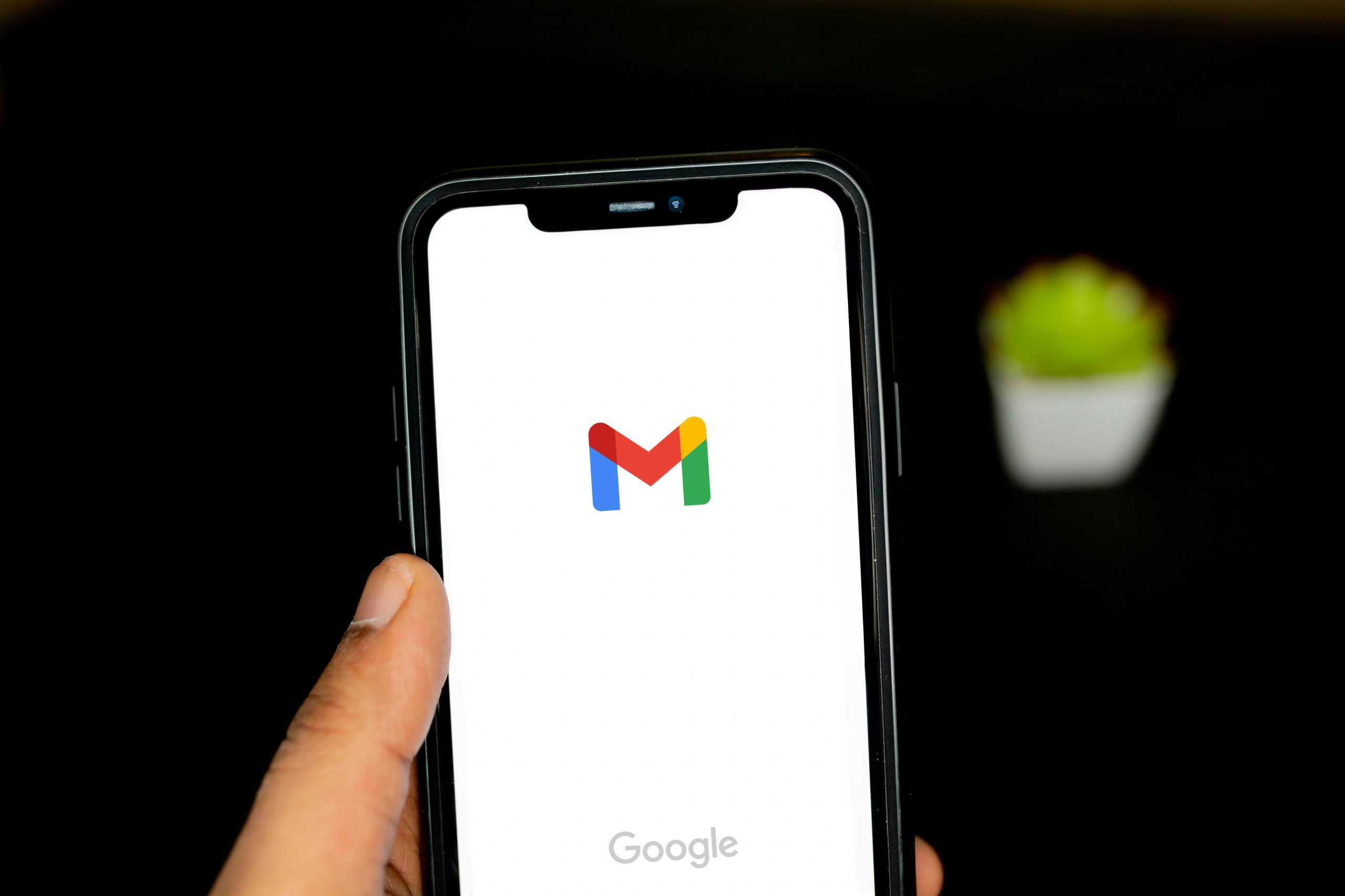Main tenant un smartphone ouvert sur Gmail